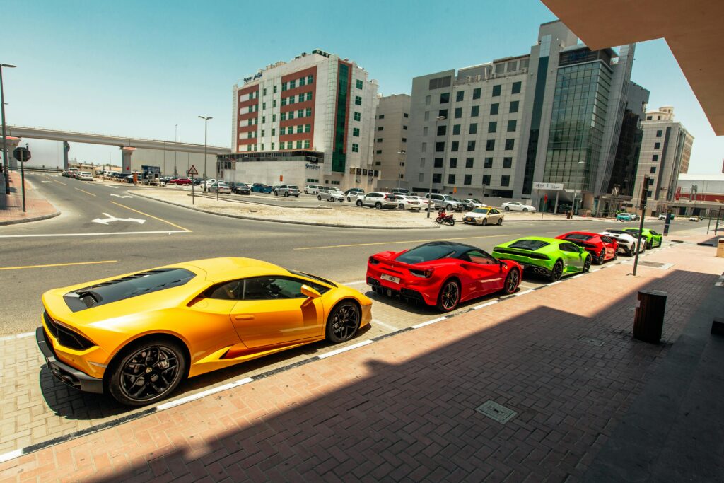 A lineup of vibrant sports cars parked on a city street in daylight.